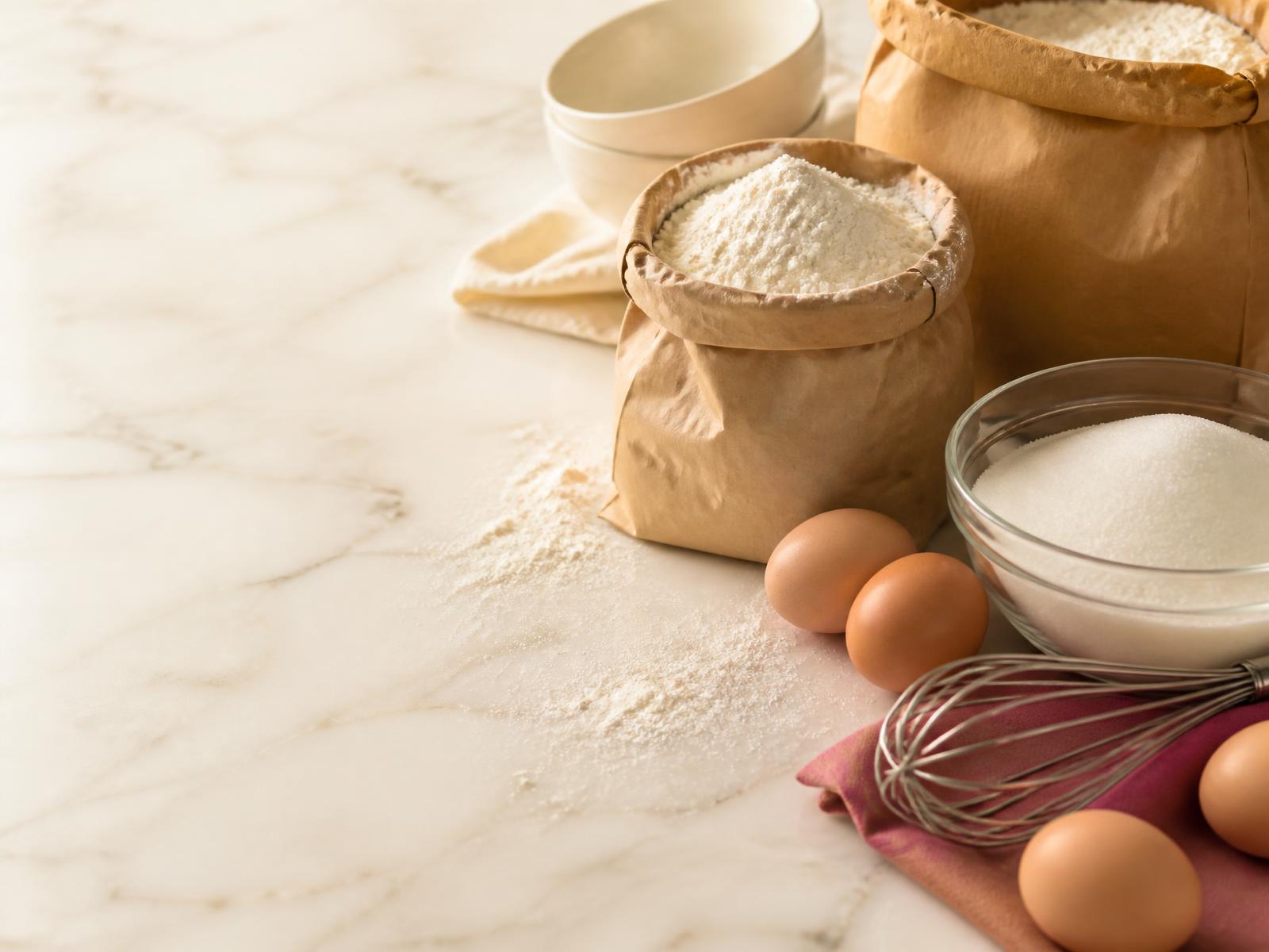 Baking ingredients — flour, sugar and eggs on a marble counter